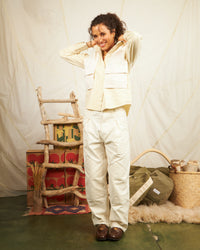 Fall collection model is wearing white denim pants with a relaxed fit, featuring a pleated waist and diamond-reinforced knees.